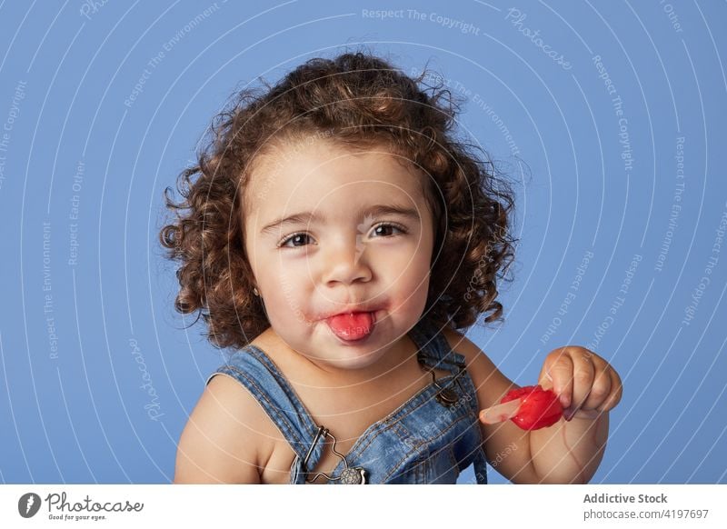 Cute little girl licking ice cream kid funny popsicle show tongue tasty treat childhood positive denim curly hair food mouth opened delicious make face adorable