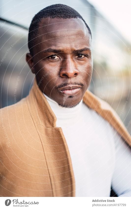 Serious young ethnic man looking at camera on street serious confident calm portrait style self assured elegant city personality fashion charismatic male