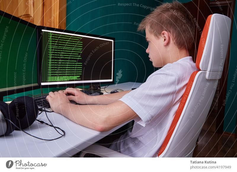 A young programmer guy prints the program code on the computer monitor screen. The concept of computer security, technology development and young professionals
