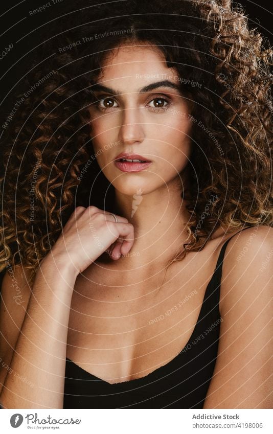 Woman with curly hair in dark studio woman appearance beauty serene natural hairstyle charming female tranquil model unemotional brown hair feminine gorgeous