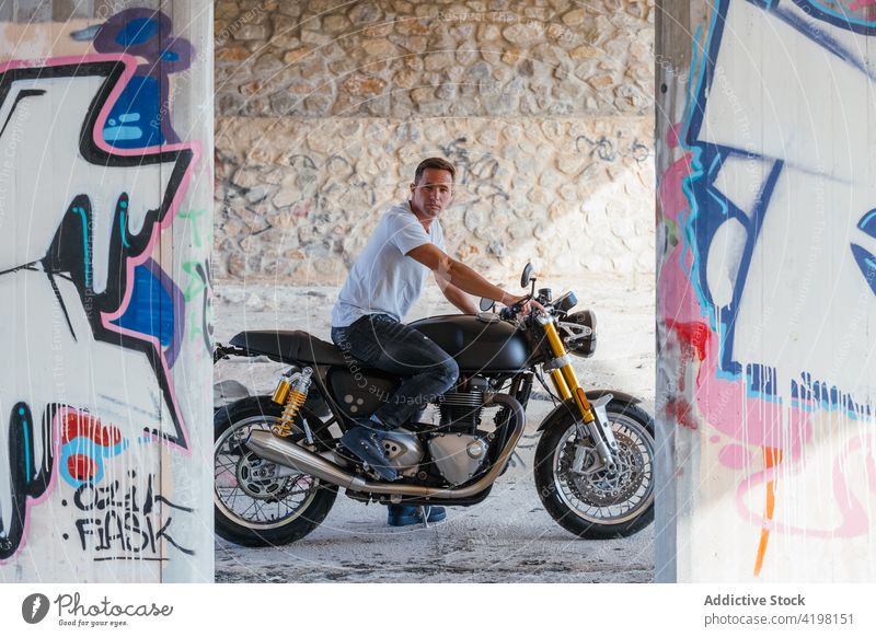 Man on modern motorbike in city biker man motorcycle cool urban style motorcyclist vehicle confident male sit brutal graffiti wall street art transport rider