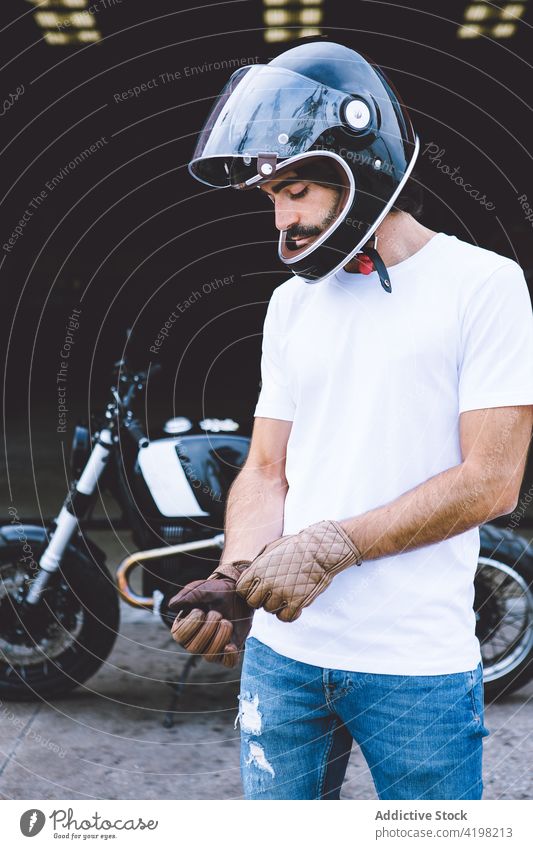Brutal young ethnic male motorcyclist wearing gloves on street man brutal concentrate motorcycle vehicle city serious style appearance personality unshaven