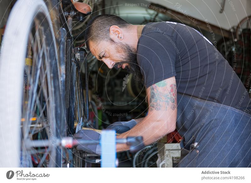 Focused man repairing bicycle in garage vehicle master prepare skill workplace professional male wheel bike rim service tire tool workshop handyman concentrate