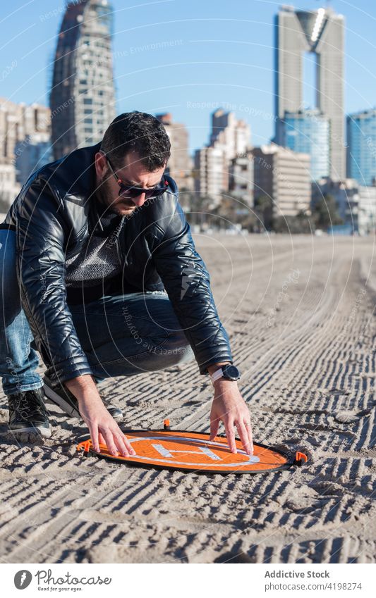 Man putting landing mat for drone on ground pad man sand protect hobby safety male concentrate focus serious sunny prepare freedom sunlight equipment