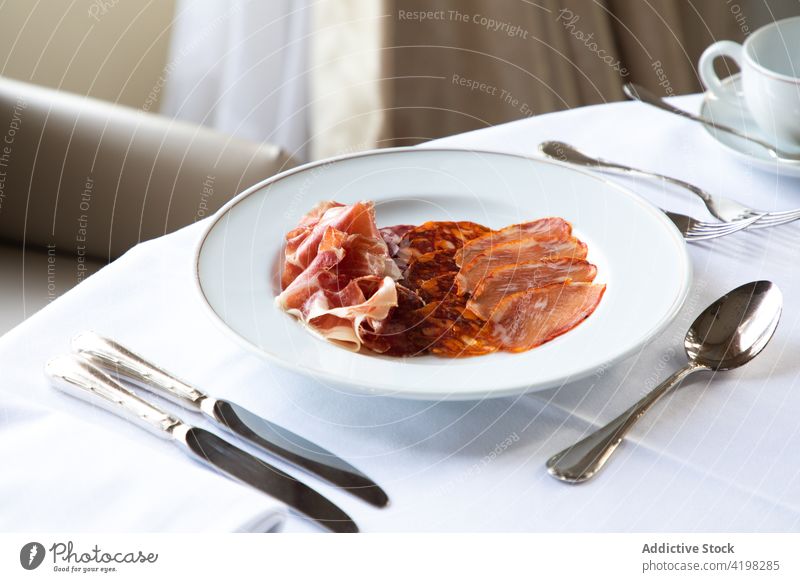 Assorted ham slices in plate served on table during breakfast coffee cutlery meat jamon chorizo restaurant delicious assorted tasty food meal cafeteria cup