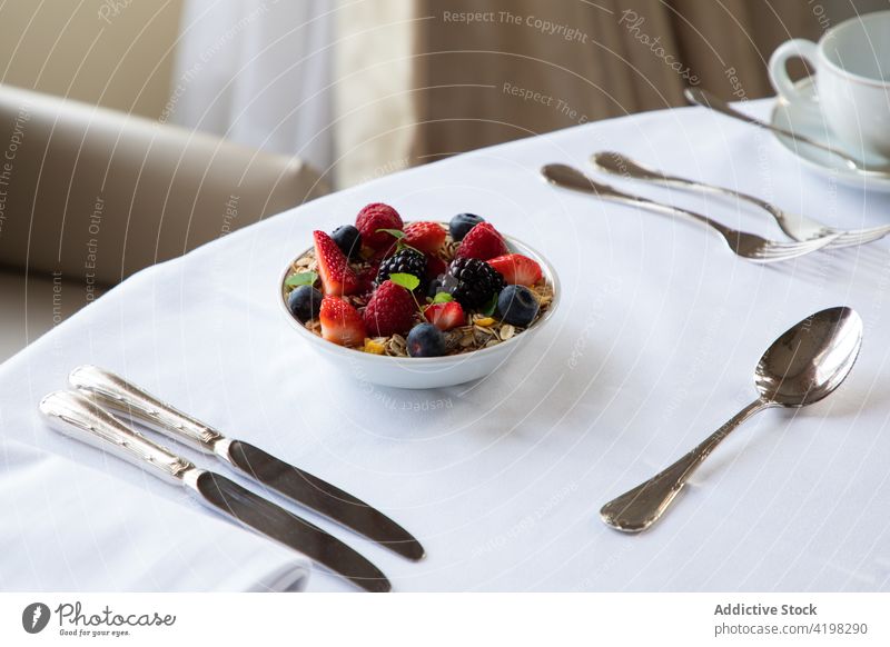 Tasty breakfast with granola bowl and berries served on table in cafe muesli berry coffee silverware super food healthy meal strawberry blueberry blackberry