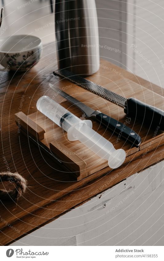 Knives with culinary syringe placed on wooden table in kitchen knife cutting board kitchenware thermos bowl tool utensil sharp cook assorted set stainless steel