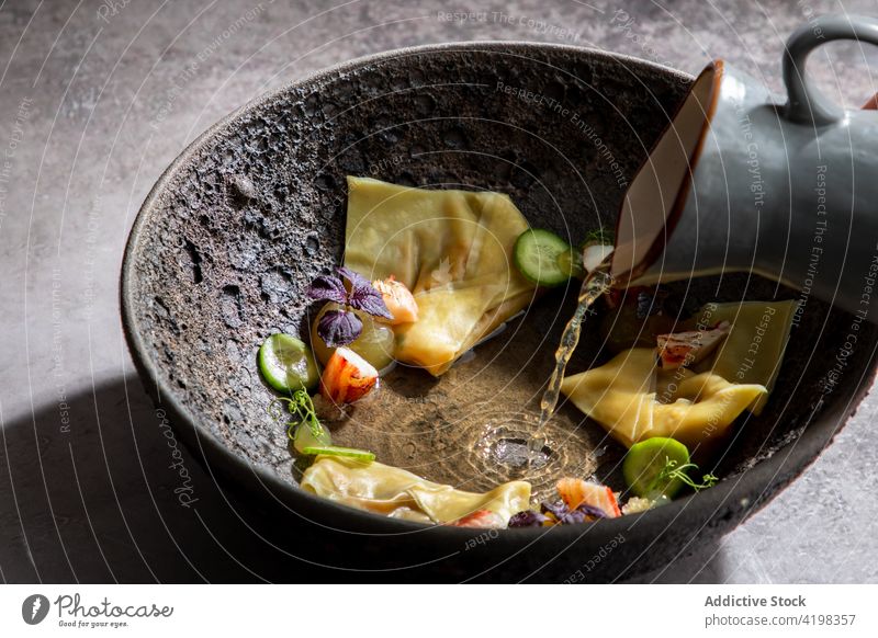 Person adding bouillon to gyoza with vegetables in bowl chef dumpling japanese meal food dish tradition broth cuisine delicious asian food prepare cook kitchen