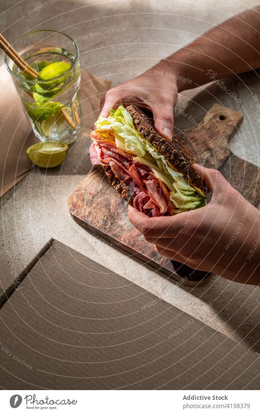 Crop person having lunch with sandwich and glass of water client toast lettuce bacon eat restaurant tasty lime fresh cafe ham food delicious portion dish meal