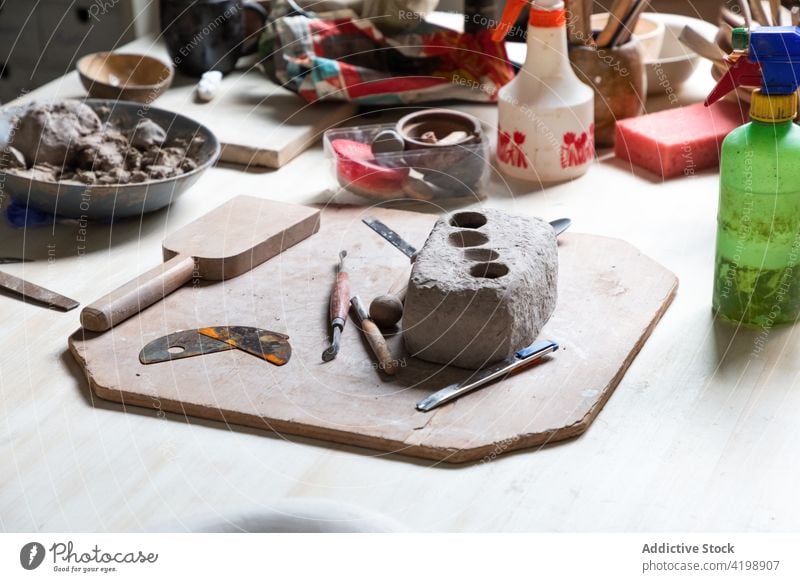 Piece of clay with assorted pottery tools placed on table in workshop clayware tableware create handicraft art craftsmanship molding creative various board