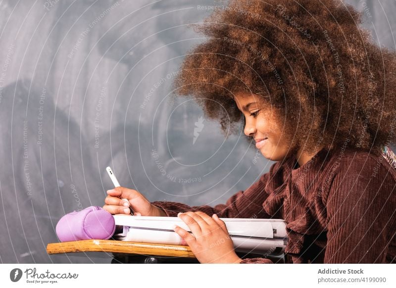 Black schoolgirl at desk in classroom lesson teenage blackboard chalkboard study education clever ethnic african american pupil learn sit table student smart