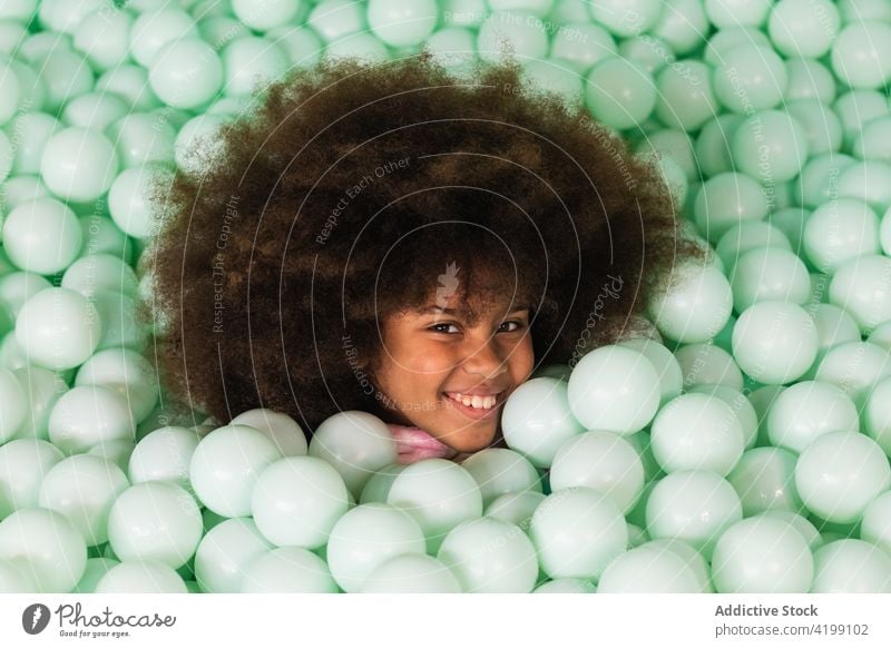 Cheerful child in ball pit play cheerful pool plastic happy afro hairstyle ethnic black african american kid fun childhood having fun enjoy content glad cute