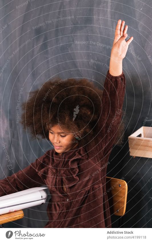 Black girl with raised hand in classroom during lesson pupil hand raised school arm raised schoolgirl study clever education ethnic african american black