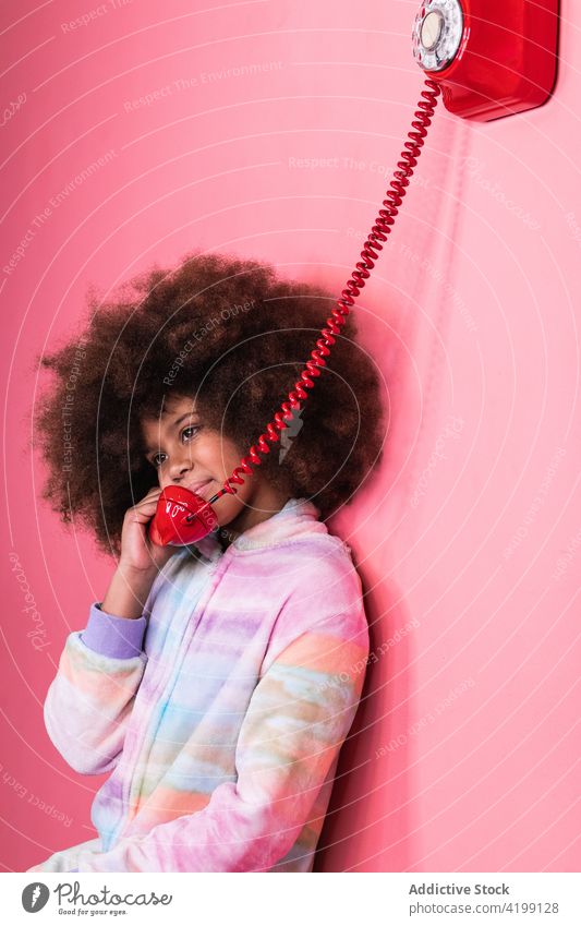 Black girl speaking on telephone in studio old fashioned talk child retro red ethnic black african american afro hairstyle call communicate joy vintage shiny