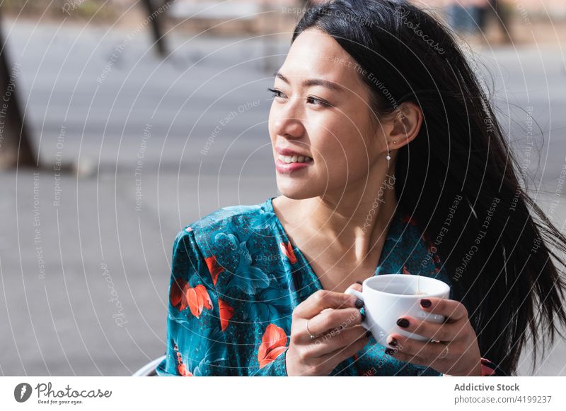Long-haired brunette Asian woman having a coffee on a terrace of a cafe asian people shop female chinese coffee shop cup person drink hot long hair spring