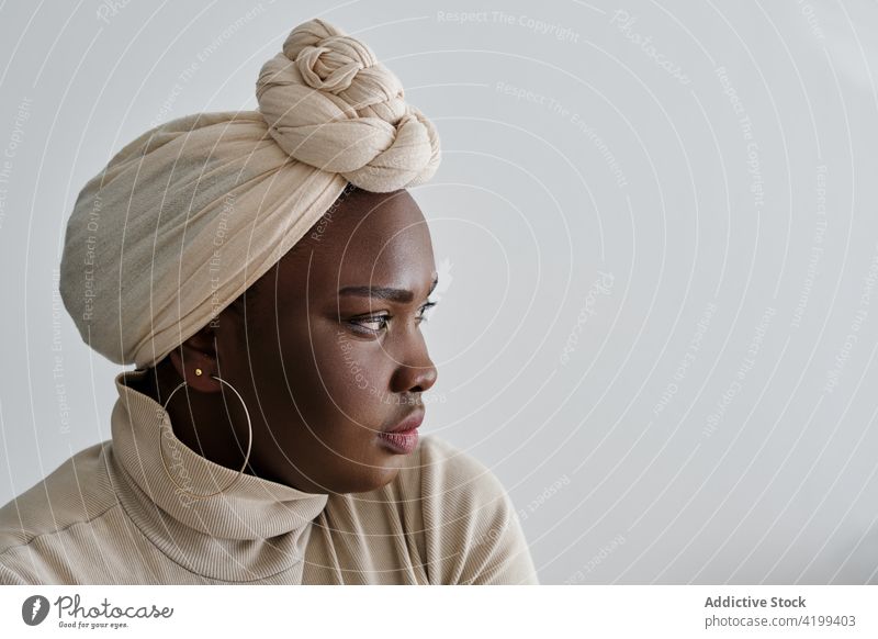 Confident young black lady in turban looking away woman style confident gorgeous model portrait appearance vogue personality feminine self assured chic female