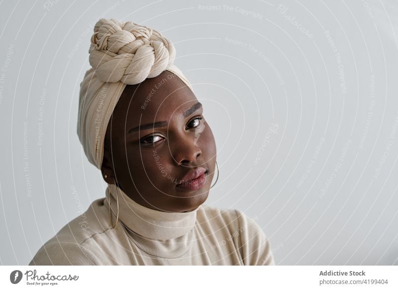 Confident young black lady in turban looking at camera woman style confident gorgeous model portrait appearance vogue personality feminine self assured chic