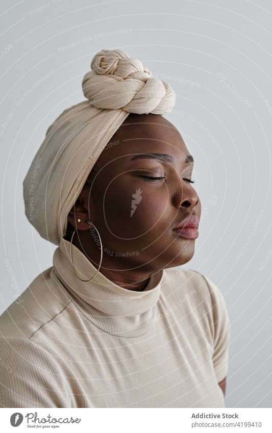 Confident young black lady in turban with closed eyes woman style confident gorgeous model portrait appearance vogue personality feminine self assured chic