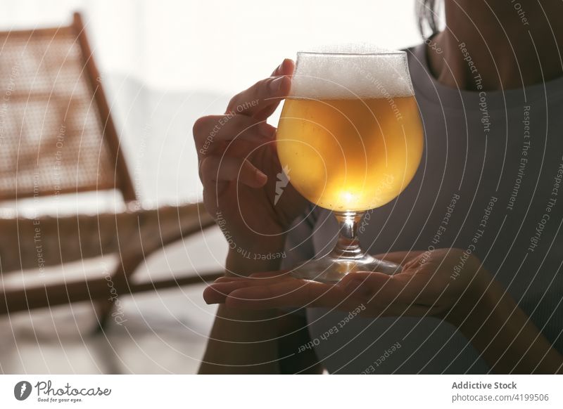 Crop anonymous woman holding glass of beer drink alcohol alcoholism home female beverage blond golden liquid healthy relax cold wellness energy fit slim brew