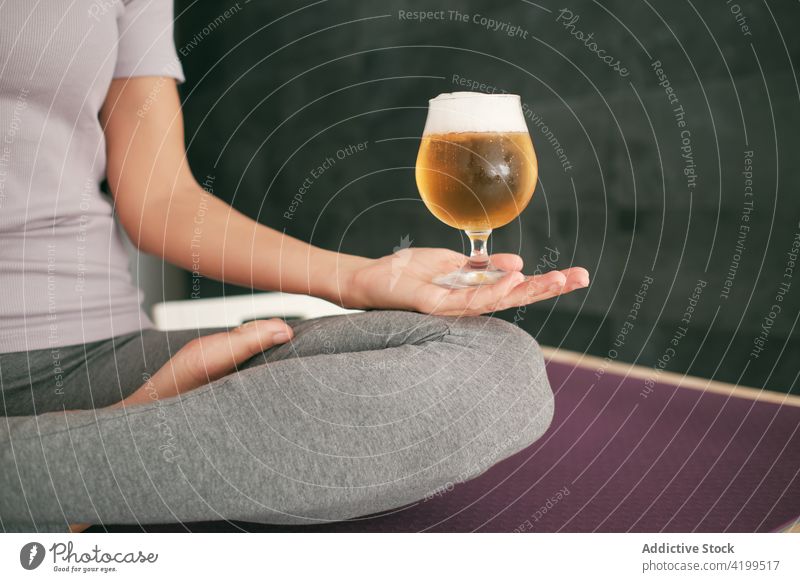 Woman doing yoga with glass of beer at home woman lotus pose meditate brew padmasana serene mudra female mat relax wellness calm healthy zen peaceful sit