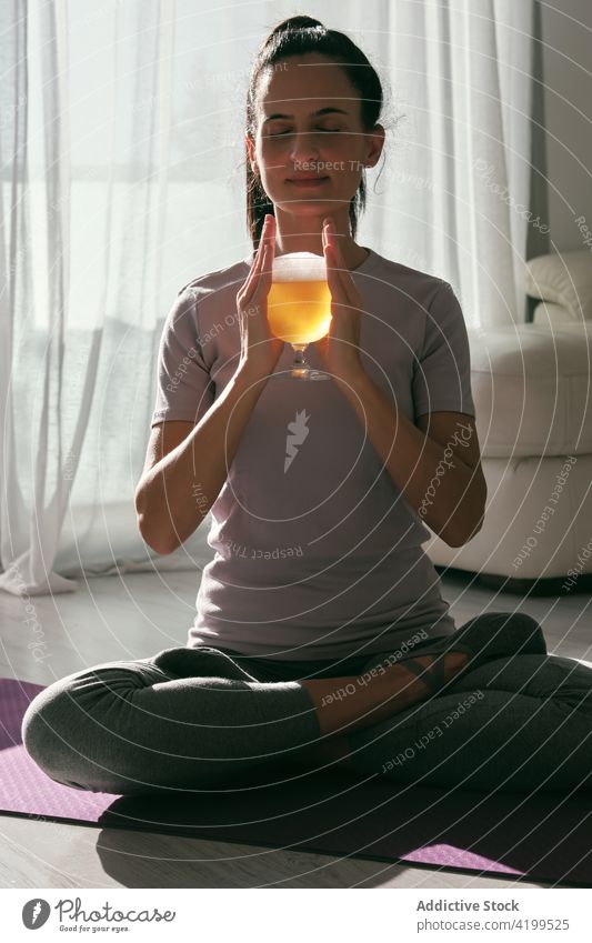 Woman in Lotus pose with glass of beer woman yoga lotus pose drink alcohol padmasana practice home female mat wellbeing eyes closed beverage sit vitality