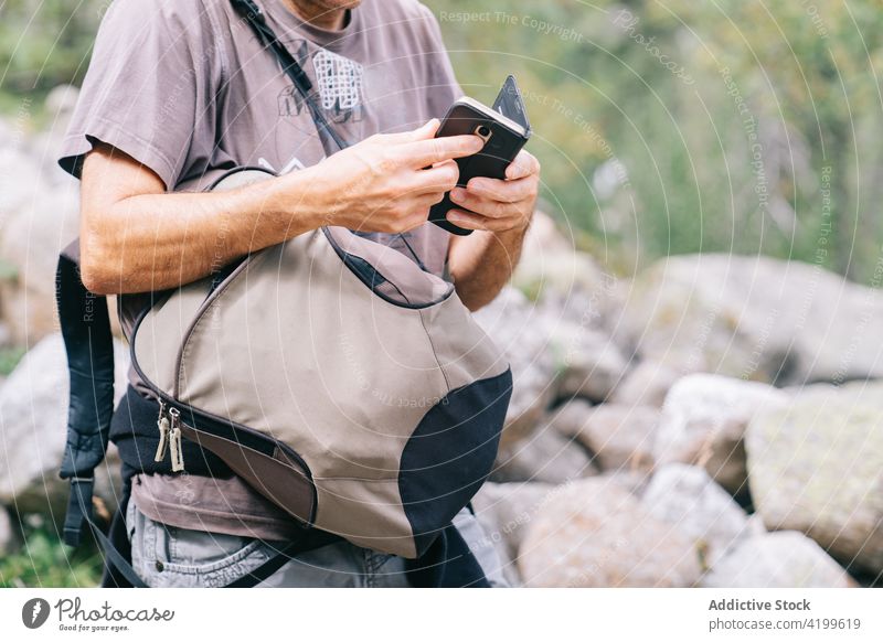 Crop backpacker on mobile phone trekker smartphone screen vacation explore man using gadget device trip wanderlust cellphone idyllic traveler hiker weekend