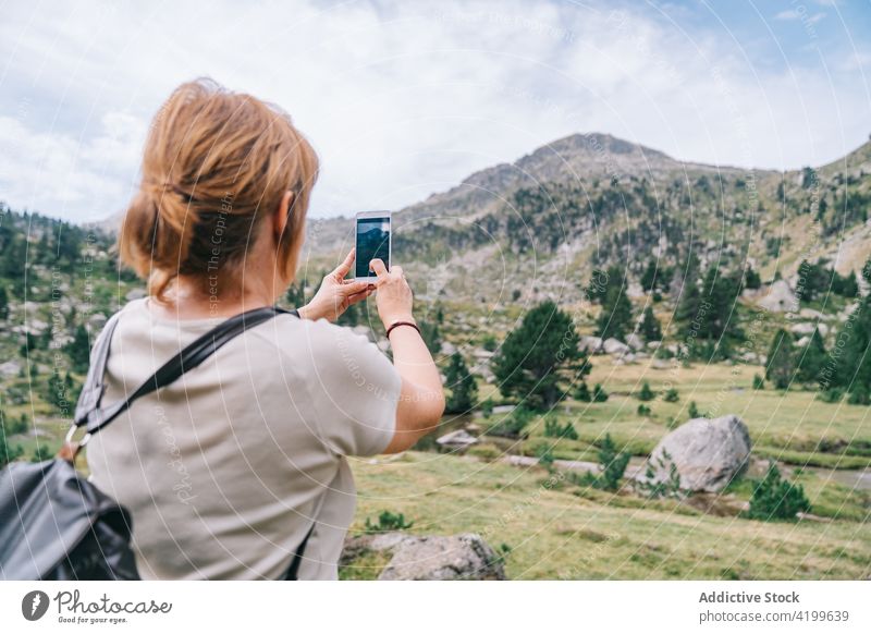Unrecognizable woman taking photo of scenic mountainous terrain take photo highland smartphone mountaineer travel memory photography backpacker amazing verdant