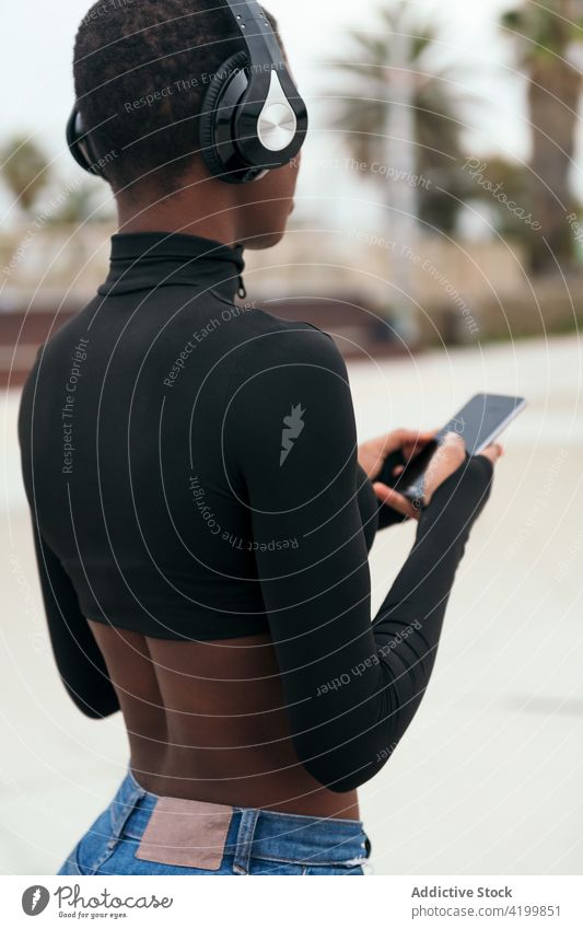 Back view black woman surfing internet on smartphone in town text messaging black screen back view short hair online pastime spare time using gadget cellphone