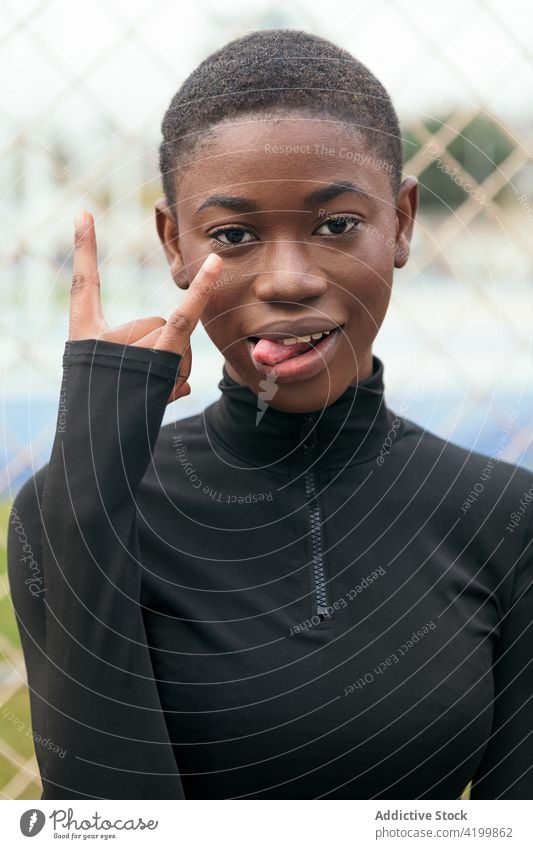 Rude black woman showing middle finger in city fuck rude rebel aggressive offensive bad gesture town outstretch smile content glad wear casual african american