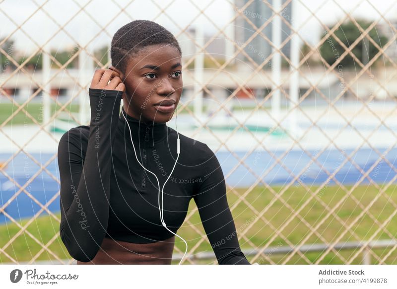 Short-haired black woman listening to music with a mobile phone and headphones african american smartphone headset song short hair portrait using gadget town