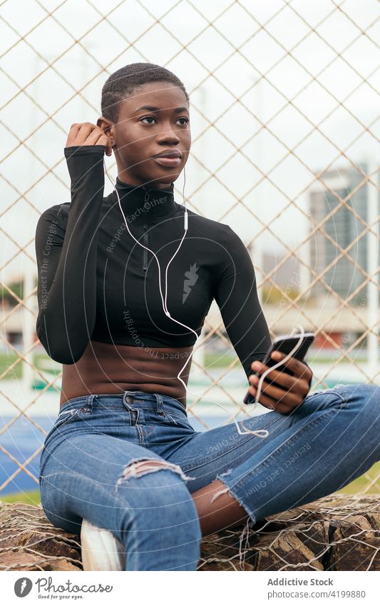Short-haired black woman listening to music with a mobile phone and headphones african american smartphone headset song short hair portrait using gadget town