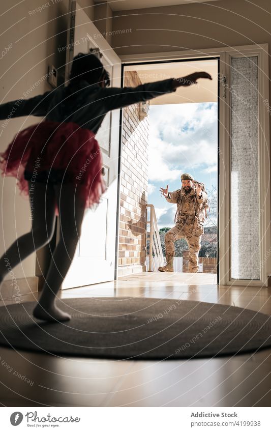 Girl running to father in military uniform daughter soldier return service entrance surprise unexpected man male doorway excited parent amazed camouflage