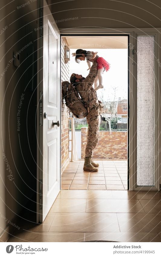 Military father playing with daughter military child serviceman soldier homecoming toss together male kid girl doorway house relationship uniform backpack