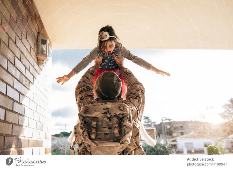 Military father playing with daughter military child serviceman soldier homecoming toss together male kid girl doorway house relationship uniform backpack