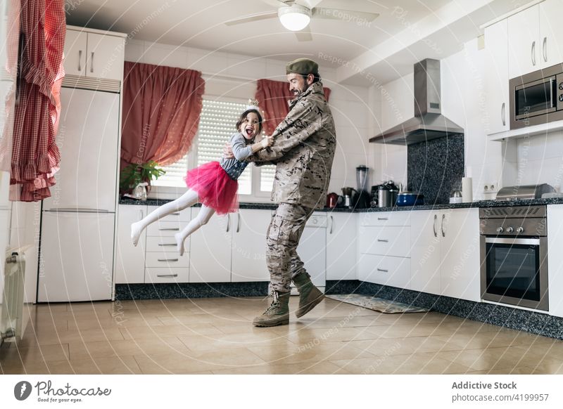 Military man playing with his daughter in the kitchen military father child serviceman soldier homecoming toss together male kid girl house relationship uniform