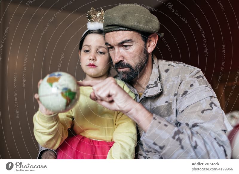 Military father pointing at place on globe daughter talk military war holding hands defend patriot soldier army man girl uniform security conflict support force