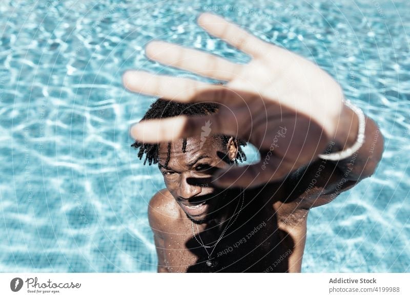 Black man covering face from sun in swimming pool summer water cover face sunny vacation naked torso holiday sunlight male ethnic black african american