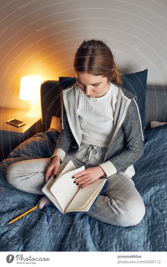 Student learning at home. Young woman making notes, reading and learning from notepad education indoor student working person female notebook studying sitting