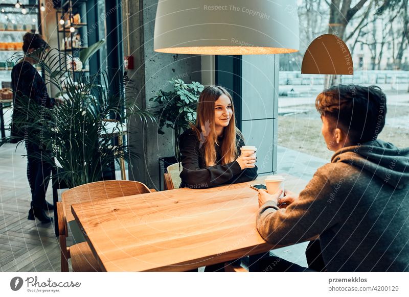 Friends having a chat, talking together, drinking coffee, sitting in a cafe. Young man and woman relaxing in cafe, having a break buy person restaurant