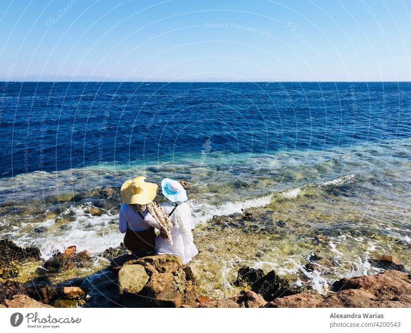 Two women in sun hat sitting by the sea Ocean Rudbeckia Summer Summery Summer vacation Summer's day Summer dress Blue Blue sky Blue-white Egypt Africa