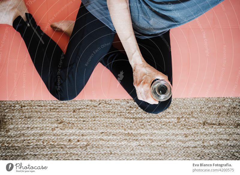 top view of mature caucasian senior woman practicing yoga pose at home. Holding bottle of water. Healthy lifestyle drinking sport healthy floor active pensioner