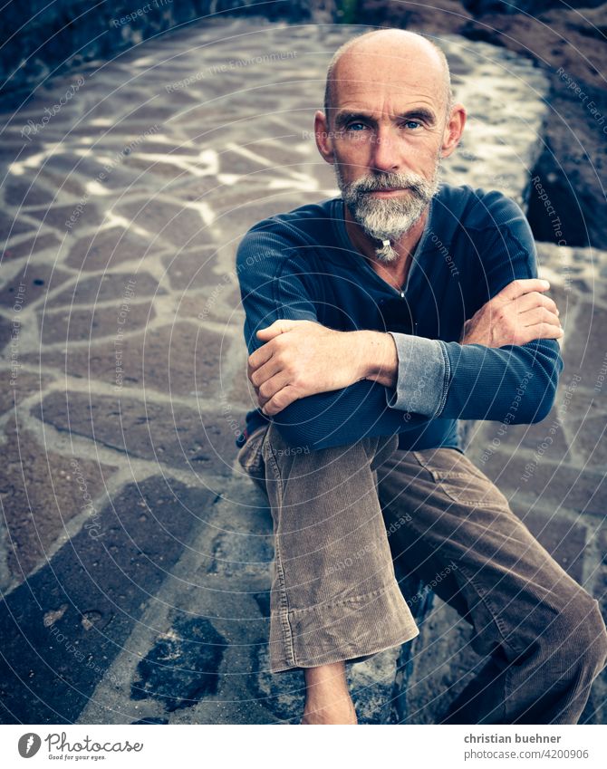 man - sitting on stone floor Man portrait sedentary arms folded Bald or shaved head Interesting Meditative relaxed