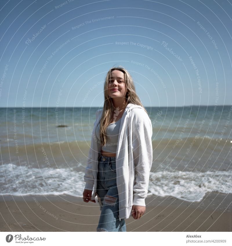 Analogue rectangular image of a beautiful blonde girl standing on the beach of the Baltic Sea and looking to the side Girl Smiling joyfully Landscape by Blonde