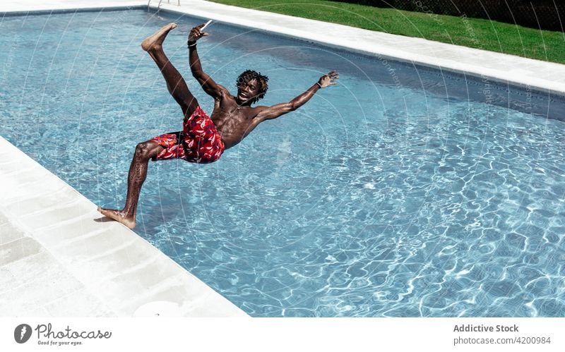 Black man with smartphone falling into pool astonish slip shock amazed browsing poolside male ethnic black african american mobile using online gadget reaction