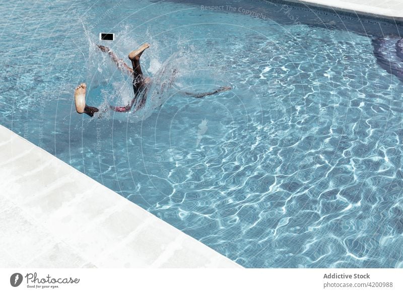 Unrecognizable black man falling into swimming pool smartphone splash water poolside waterdrop male ethnic african american mobile online gadget guy slip