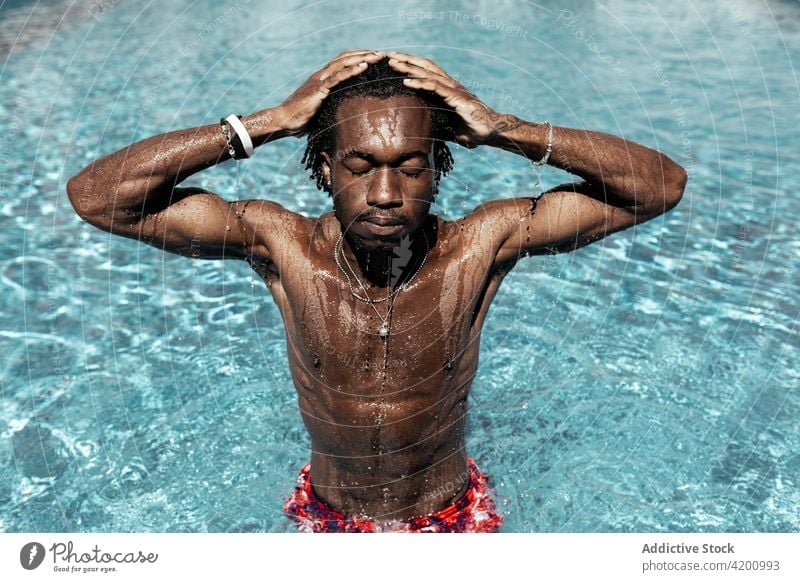 Black man in swimming pool summer vacation enjoy water naked torso carefree sunny shorts male ethnic black african american holiday recreation eyes closed