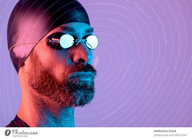 Side view studio portrait of a swimmer with cap and goggles man background glasses bearded healthy face young isolated white people one athlete lifestyle sport