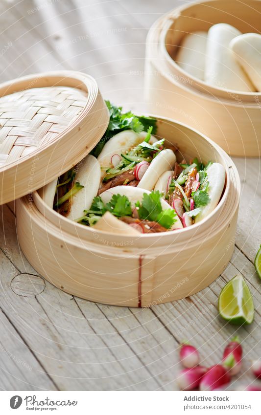 Delicious bao buns with filling in bamboo steamers asian food lunch dinner meal menu delicious baozi meat radish cucumber fresh slice lime herb citrus fruit