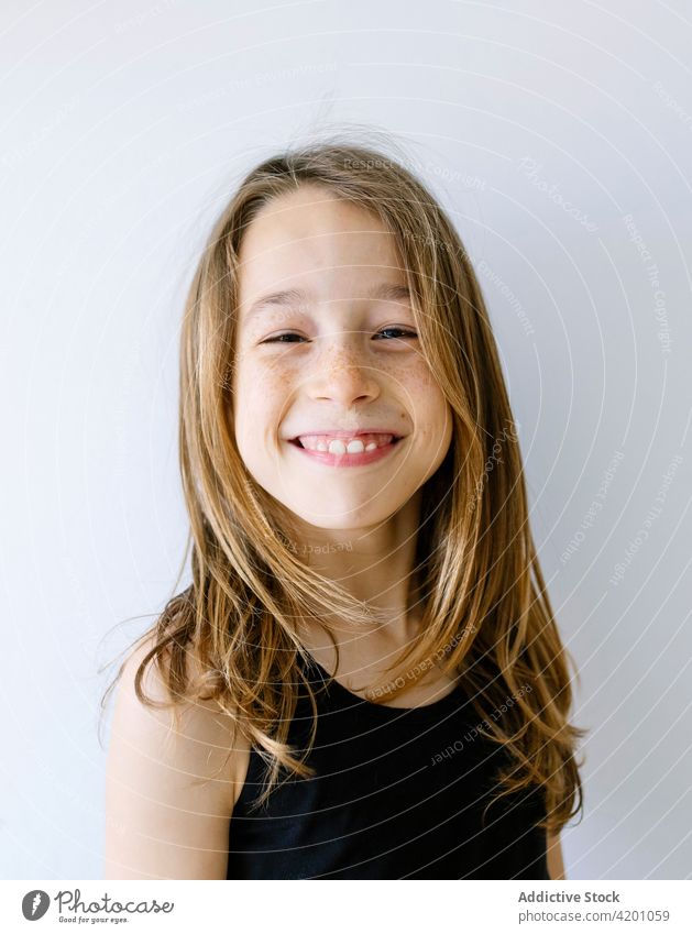 Happy girl with long hair and freckles against white background child laugh cheerful excited portrait fun joy humor delight positive toothy smile optimist