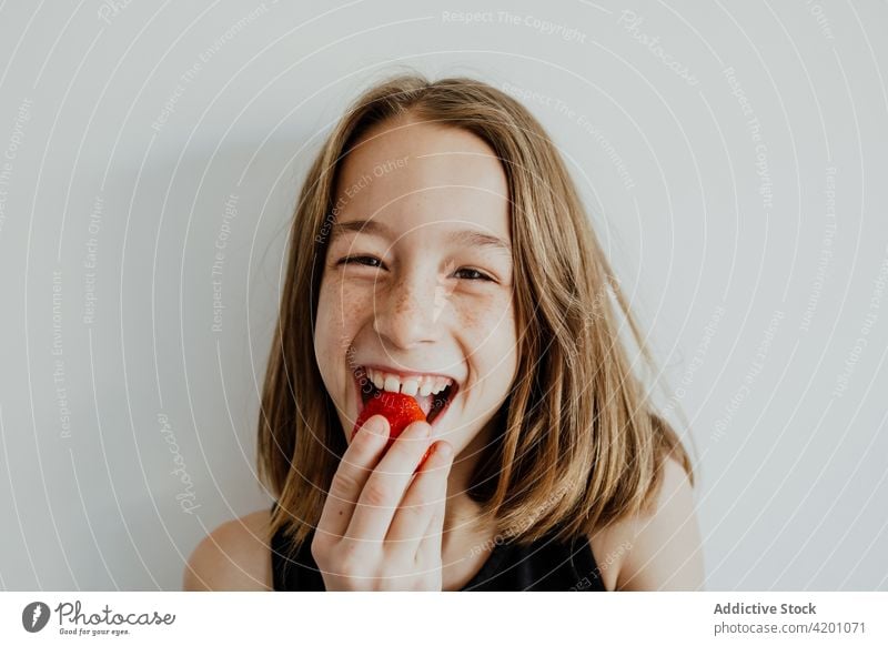 Excited girl eating strawberry and smiling smile delicious delight enjoy fruit portrait cheerful bite yummy optimist food glad sweet tasty teen kid freckle